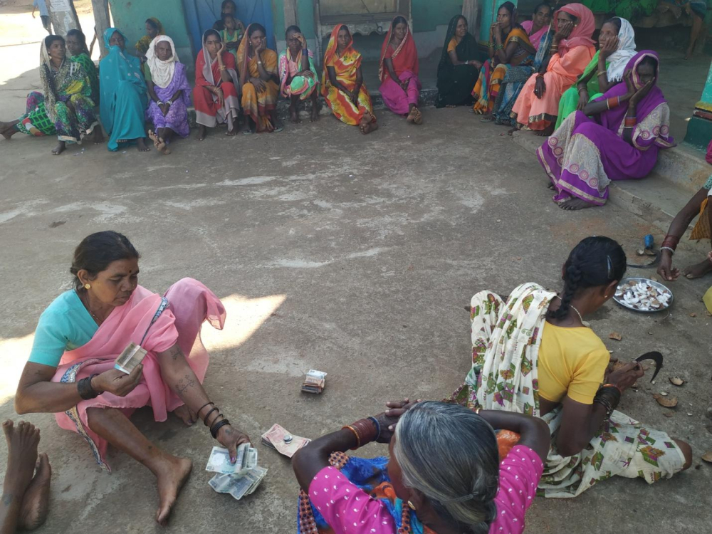 After selling the grains, the amount is being calculated so that every woman in the village will get their share of money. 