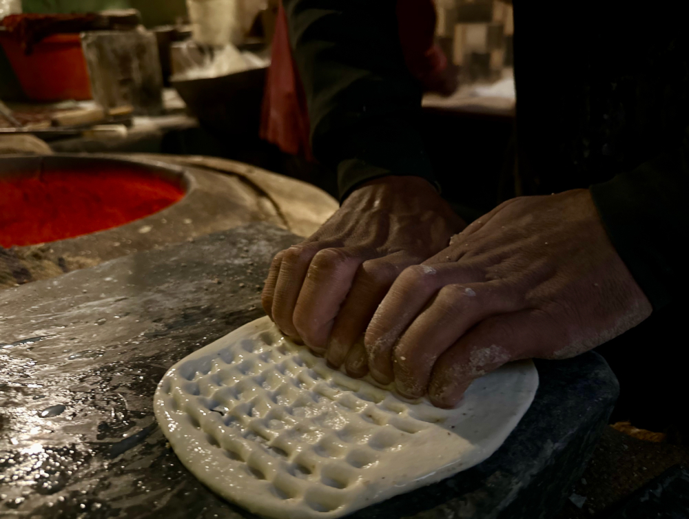 Crafting indentations on flattened dough on a marble base. (Picture Credits: Taha Mughal)