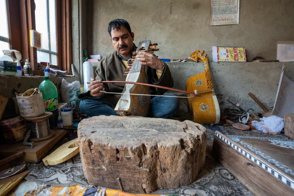 A sarangi maker testing the soulful resonance of his handcrafted instrument. 
