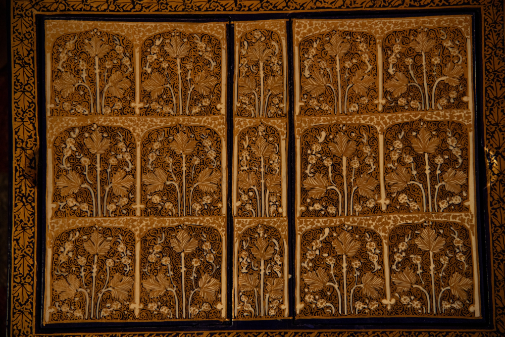 Papier-mâché artifacts featuring symmetrical geometric and floral motifs, painted in vibrant hues and gold detailing.