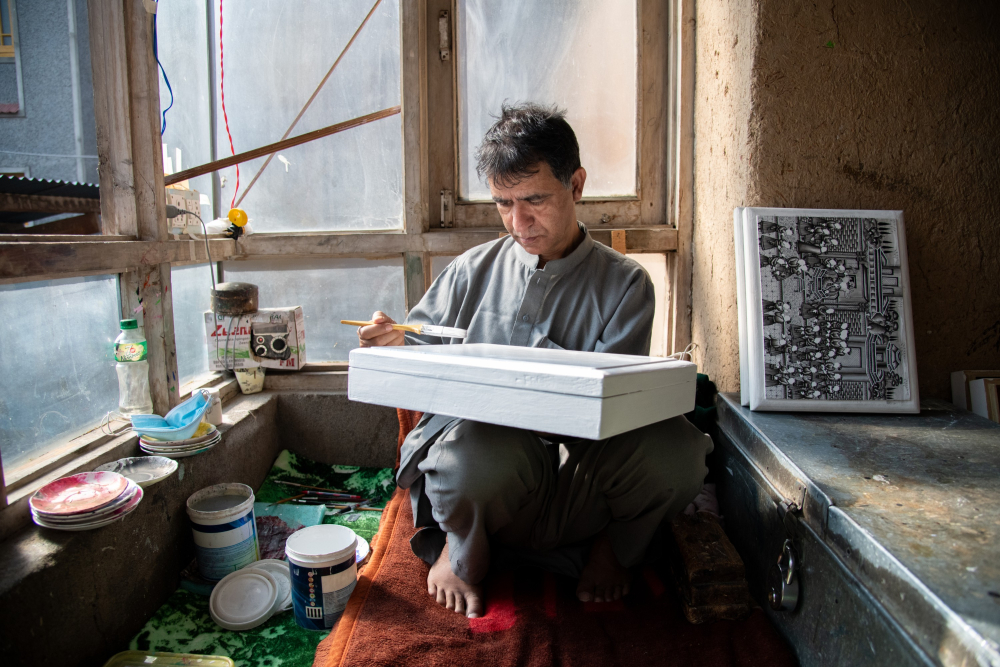 ​   ​An artisan paints papier-mâché using fine brushes and natural pigments. 