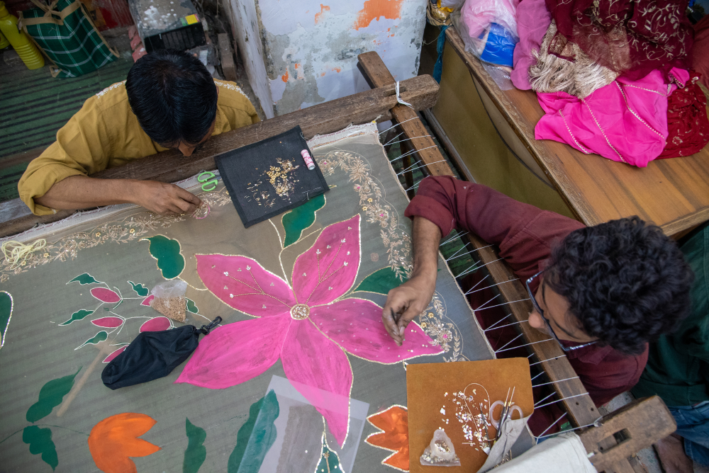 Artisans executing Zardozi work which involves the use of metallic wires (zari), needles, and adda (wooden frame) to create raised motifs on fabric. (Picture Credits: Monis Khan)