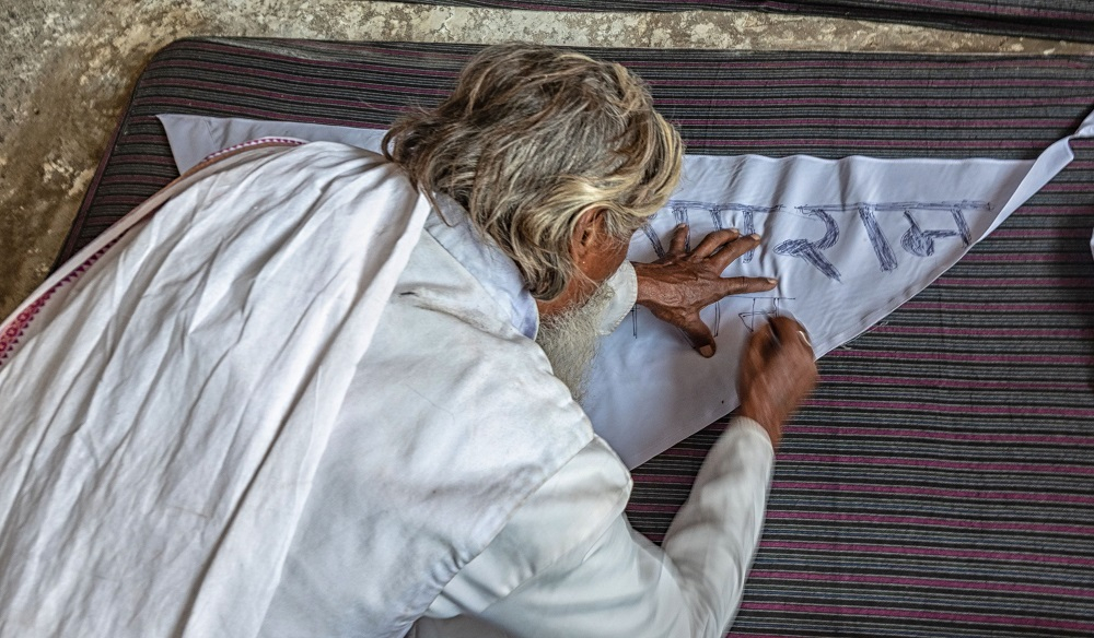 A Ramnami Inscribing Ramram on a piece of Drapery