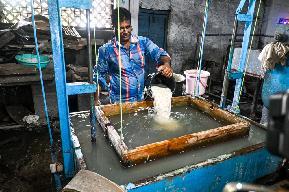 Mohammad Altaf pours the pulp into the frame of the vico vat machine which is operated by hand. (Picture Credits: Anil Purohit)