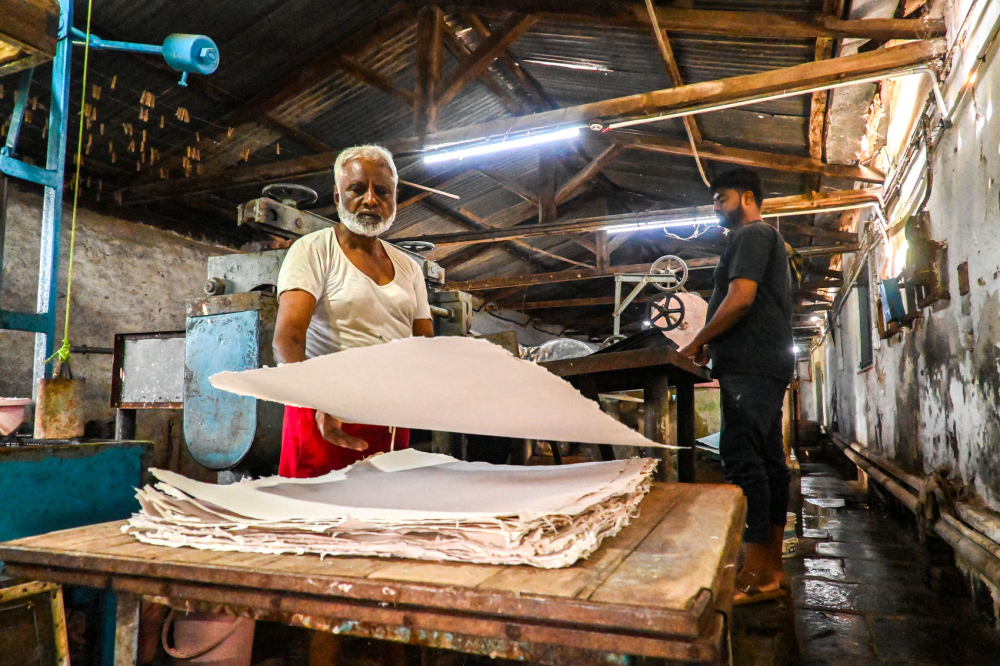 Gawas Khan stacks paper that was straightened and cut. (Picture Credits: Anil Purohit)