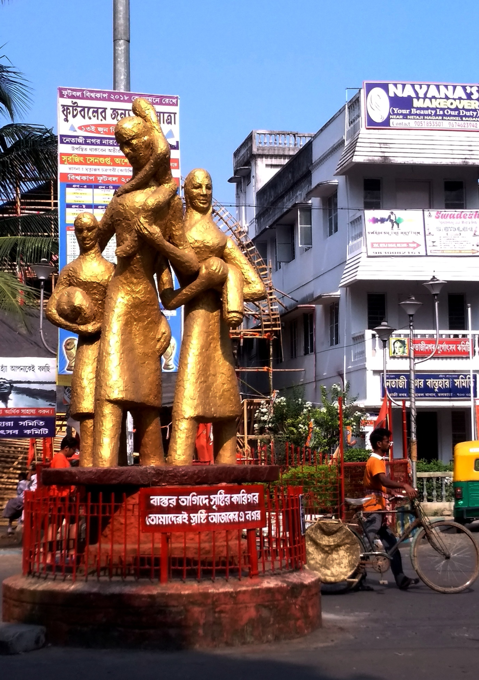 Fig. 4: Netajinagar: The refugee statue and the colony committee office on the right-hand corner. Behind the statue is a glimpse of the pandal of the colony committee puja being made. Courtesy: Priyankar Dey