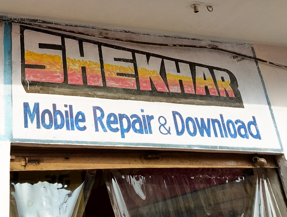Fig. 8. The signboard for Shekhar, a mobile repair shop in Chandni Chowk, has the eye-catching features of cinema title design. The red, white, and yellow used to fill the letters resemble the effect of crayons and the thick black shading encases the lettering and pronounces its shape. 