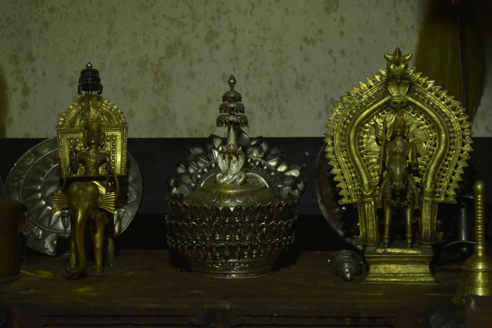 Fig 2: A shield, a silver crown, a bell, and statues of the guardian spirits, Baiderlu (riding an elephant) and Kodamanithaya at the daivakone of Kallya Guttu. The room also houses other materials not kept in a decorative manner, such as a bronze cradle and swords.