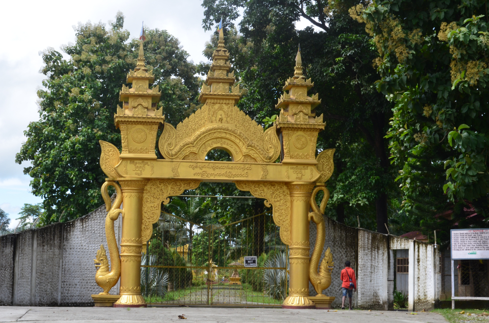 Fig. 1: Entrance gate of the Kongmu Kham (golden pagoda monastery), Tengapani, Arunachal Pradesh. Theravada monasteries of Arunachal Pradesh are distinguishable from the surrounding village dwellings and other structures by their attractive architecture. The entrance gates of these monasteries are decorated with Buddhist symbols and floral ornamental patterns and their boundaries are marked with bamboo fencing or concrete walls (Courtesy: Ajanta Das)
