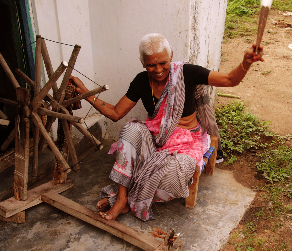 A spinner on her traditional charkha. She turns the wheels of the charkha with her right hand, while she draws and twists the cotton to make yarn with her left hand before winding it around the spindle (Courtesy: Samyuktha Gorrepati)