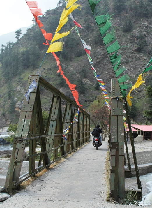Fig. 1: One of the bridges leading to Bagori. The village is accessible only on foot or on a two-wheeler. The Tibetan prayer flags fluttering on the bridges showcase the probable Buddhist influence (Photo: Sweta Kandari)