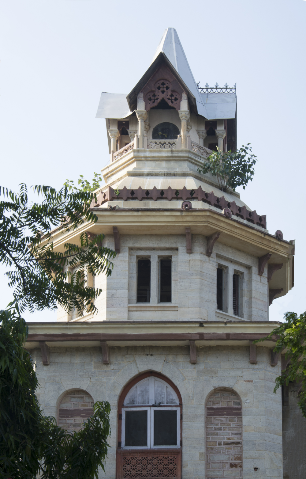 Fig. 3: The top floor of the Mayo Hospital ghanta ghar shows the black iron, circular clock face, partially covered by the balcony railing. The clock is not in a functioning condition anymore