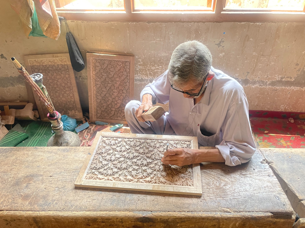 Artisans in Lal Bazar skillfully carve walnut wood using traditional tools.