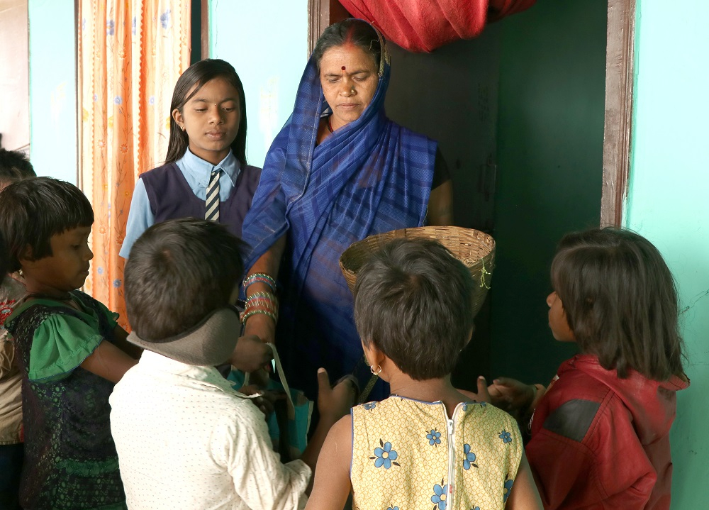 Children receiving grain from a house lady
