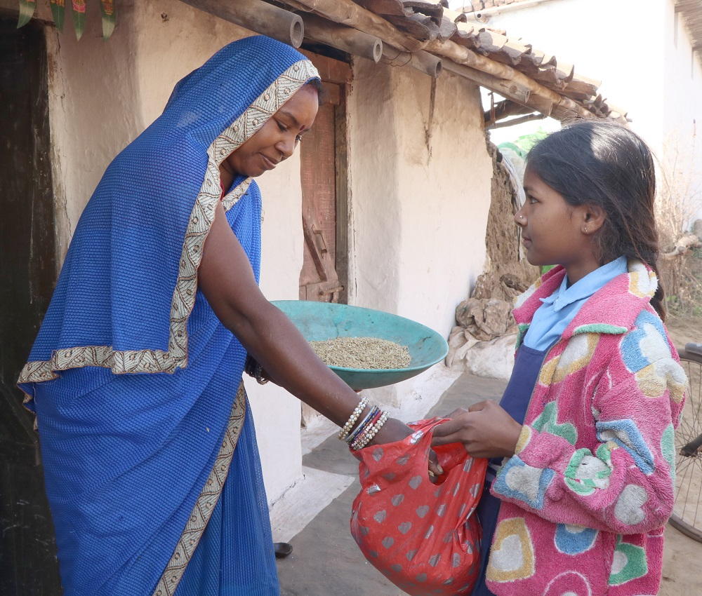A girl receiving grain from a house lady during Chheri Chhera