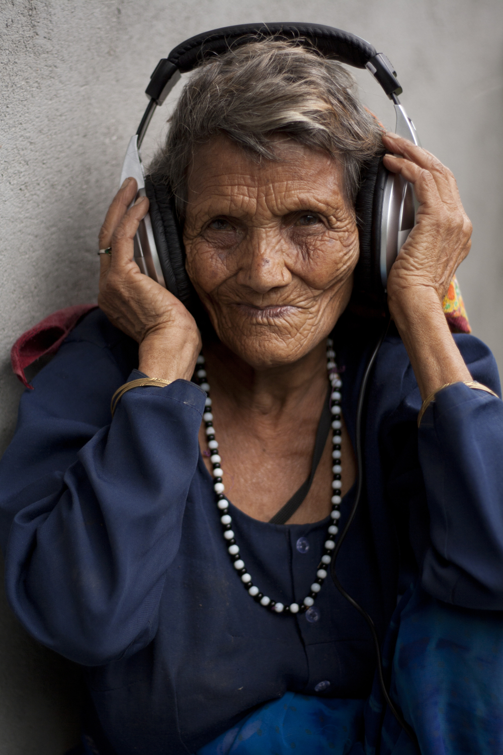 Fig. 1: Maagi Devi was a local Bagadwali singer from Jaikhandi village, Rudraprayag, who recently passed away. She was one of the first folk musicians to record a song for the community radio station when People’s Power Collective and Mandakini ki Awaaz commenced their field visits in 2013. Here, she is listening to her voice being played back to her for the first time (Photograph by Shweta Radhakrishnan/ Courtesy: People’s Power Collective)