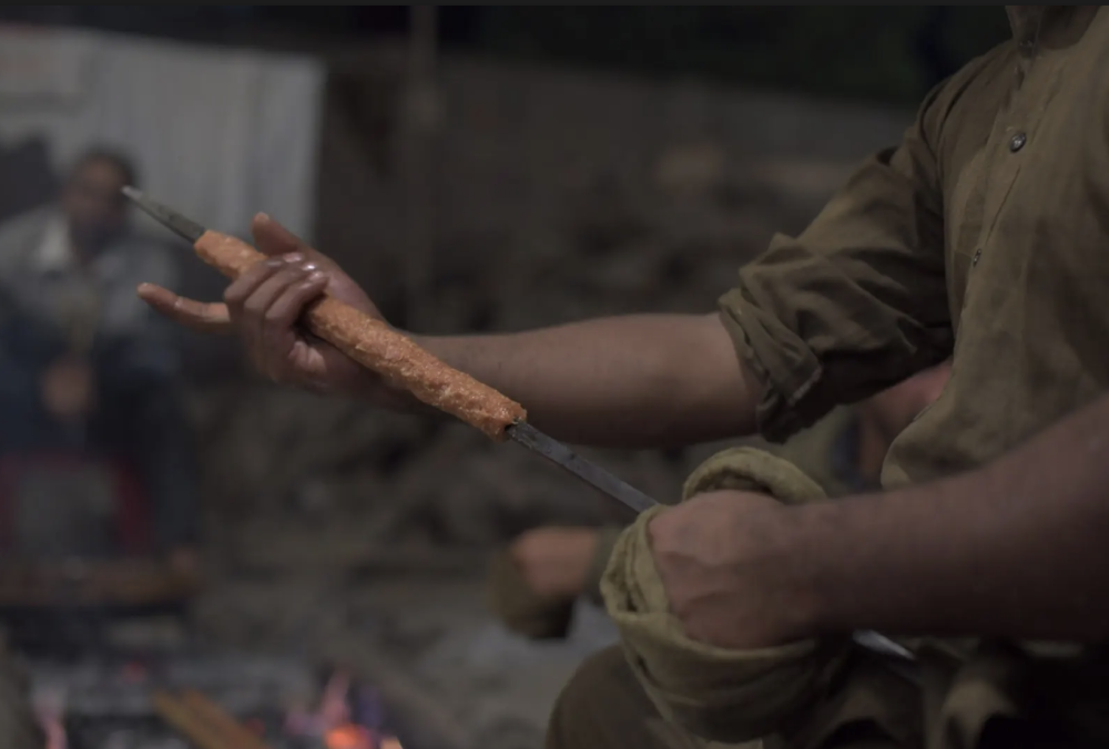 A waza expertly shaping seekh kebab on a skewer. 