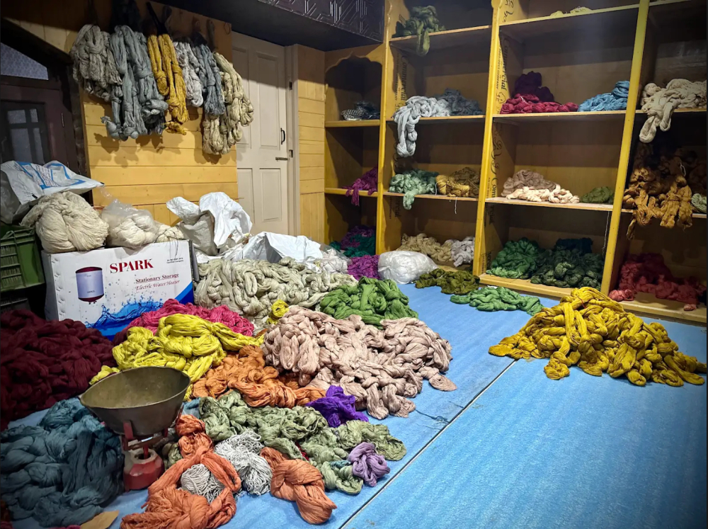 A glimpse inside a carpet karkhana, with bundles of vibrant yarn awaiting the loom.