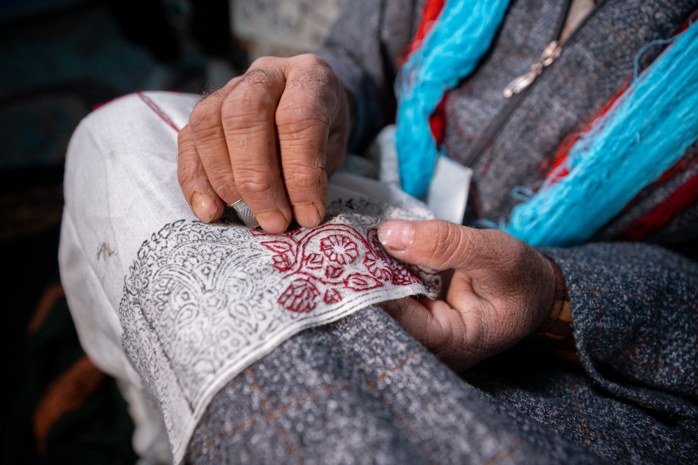 A sozni artisan stitches delicate patterns inspired by Kashmir’s natural beauty onto fine Pashmina. 
